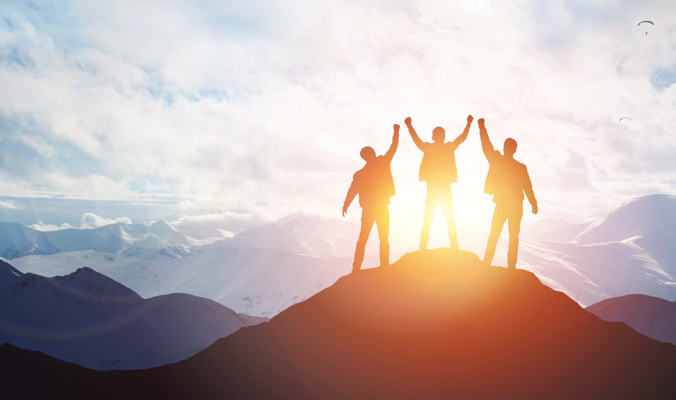 Three business men celebrating on a mountain